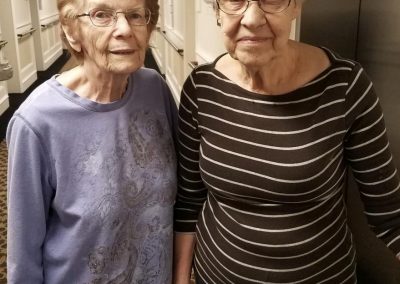 two elderly women pose next to elevator