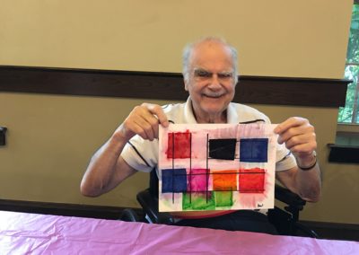 elderly man holds up his painting