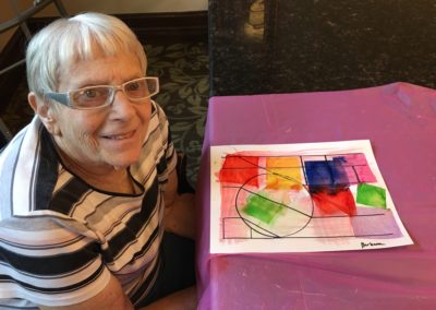 elderly woman poses with painting
