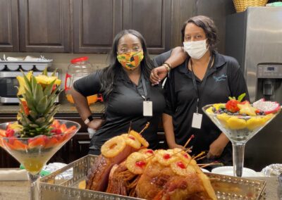 women in masks pose next to food buffet